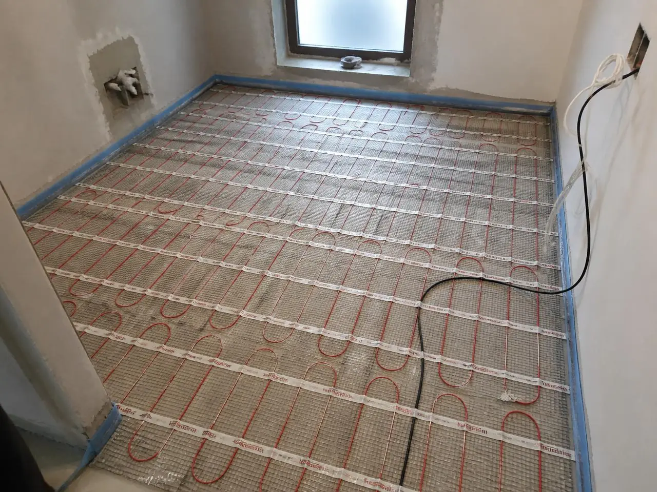 Radiant floor heating mat installed before tile during an NYC bathroom flooring installation