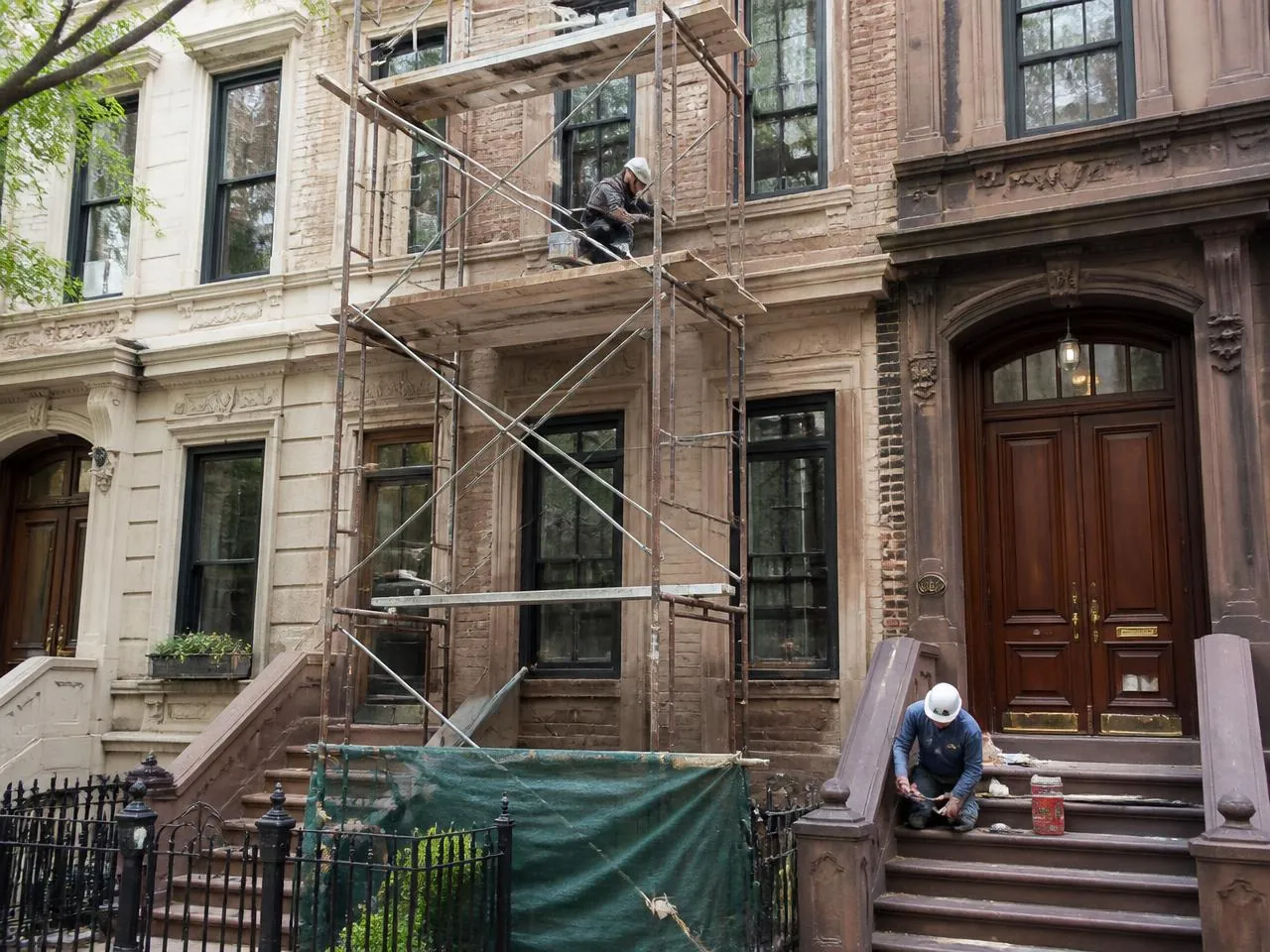 Townhouse renovation cost NYC — limestone and brownstone facade restoration with scaffolding and stoop repair