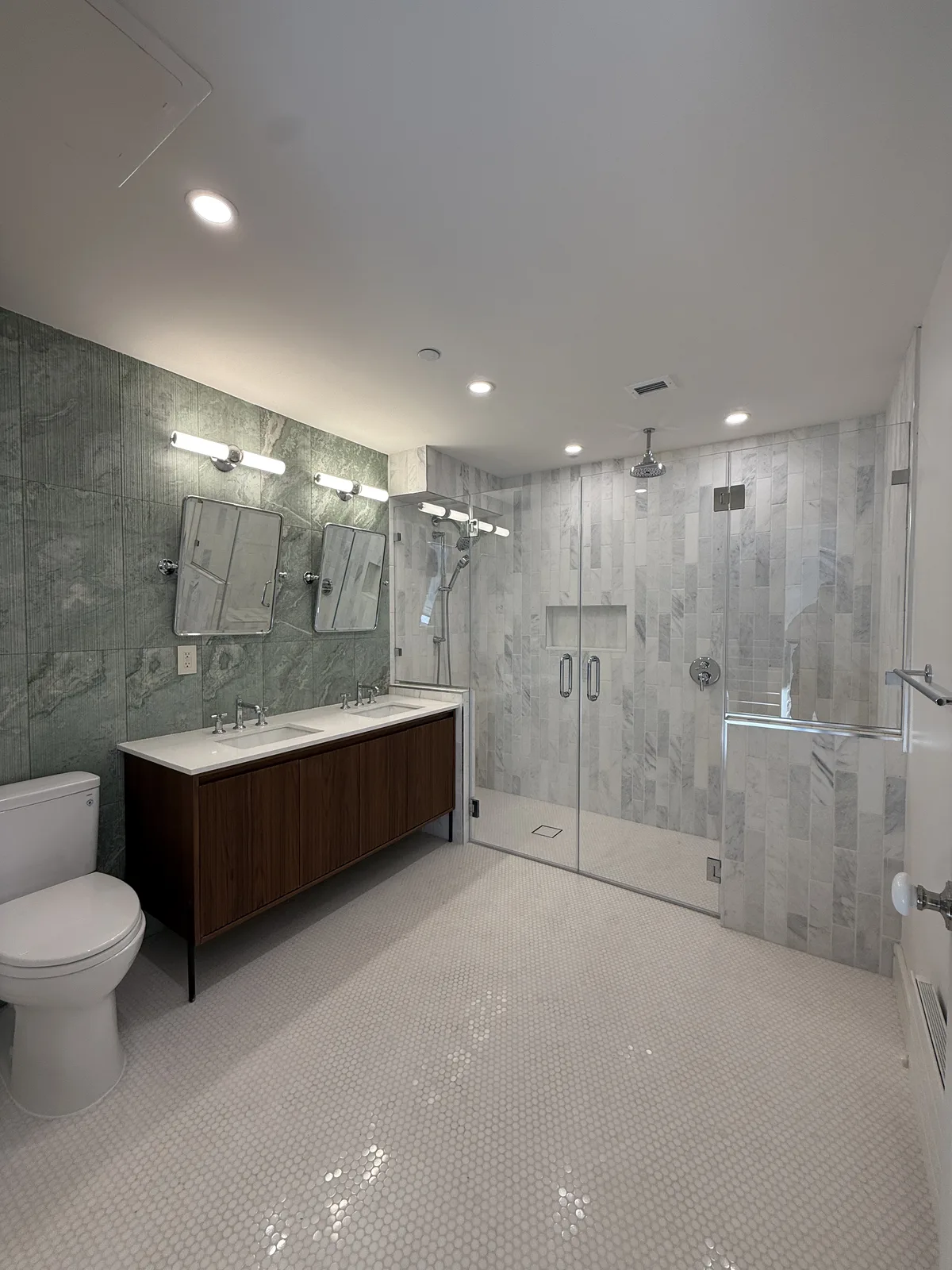 Finished bathroom renovation with marble tile, glass walk-in shower and walnut double vanity in New York City