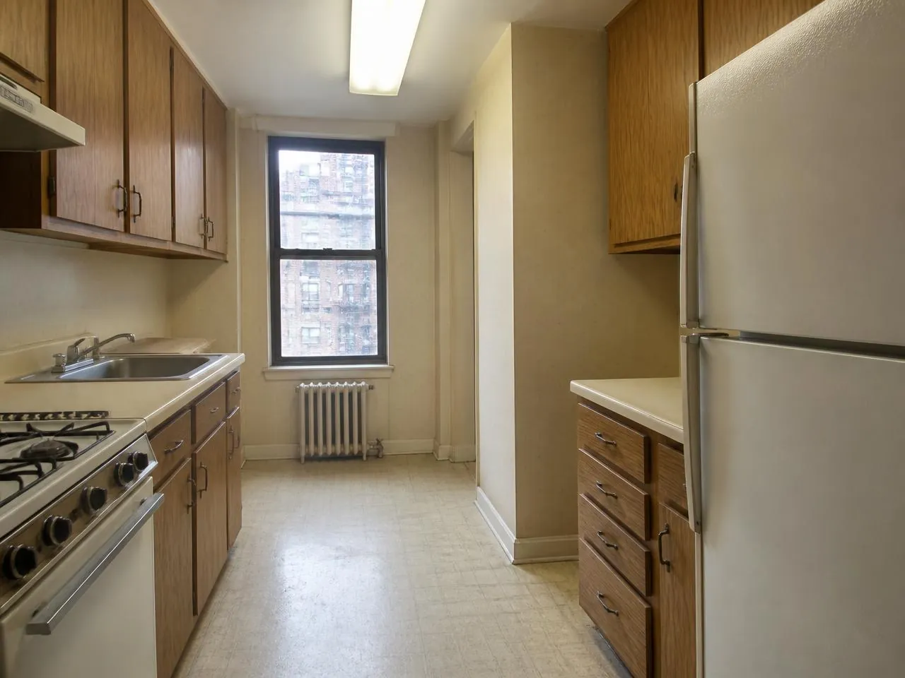 Before a kitchen remodel NYC with dated laminate cabinets, worn vinyl floor and old appliances