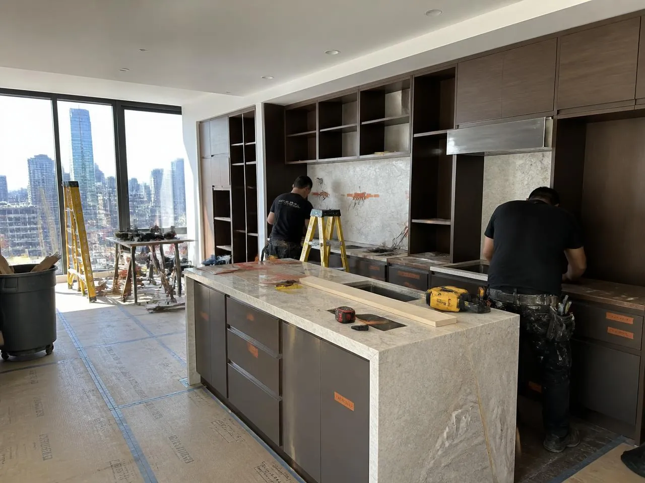 Contractors installing custom millwork and a stone countertop during a luxury downtown Manhattan apartment renovation