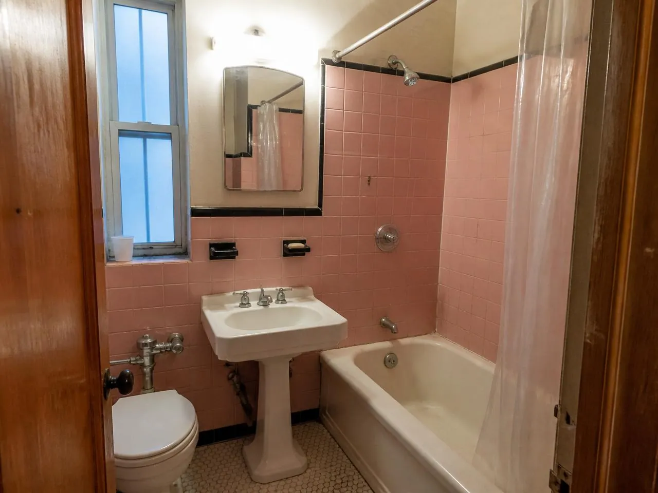 Bathroom renovation NYC before photo of a dated pre-war apartment bathroom with pink tile and tub-shower combo