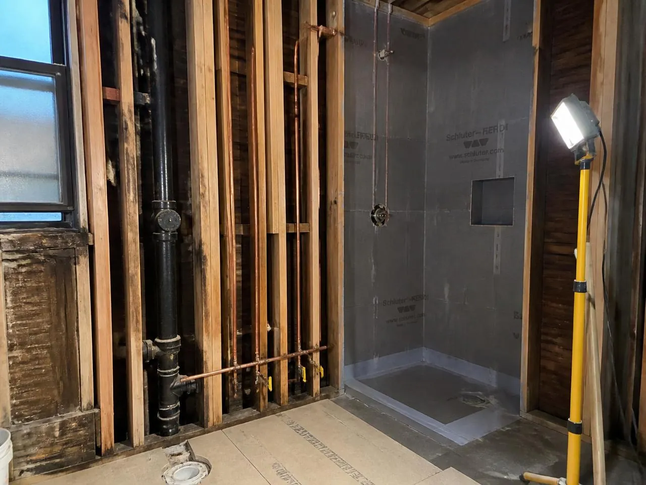 Condo bathroom renovation NYC with cast iron stack coordination and waterproofing membrane