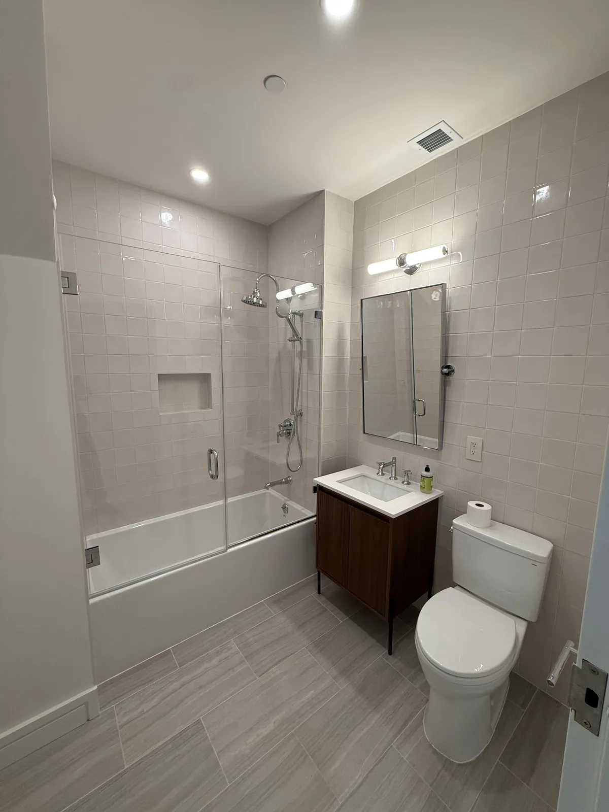 Completed bathroom renovation with subway tile and glass tub enclosure in New York City