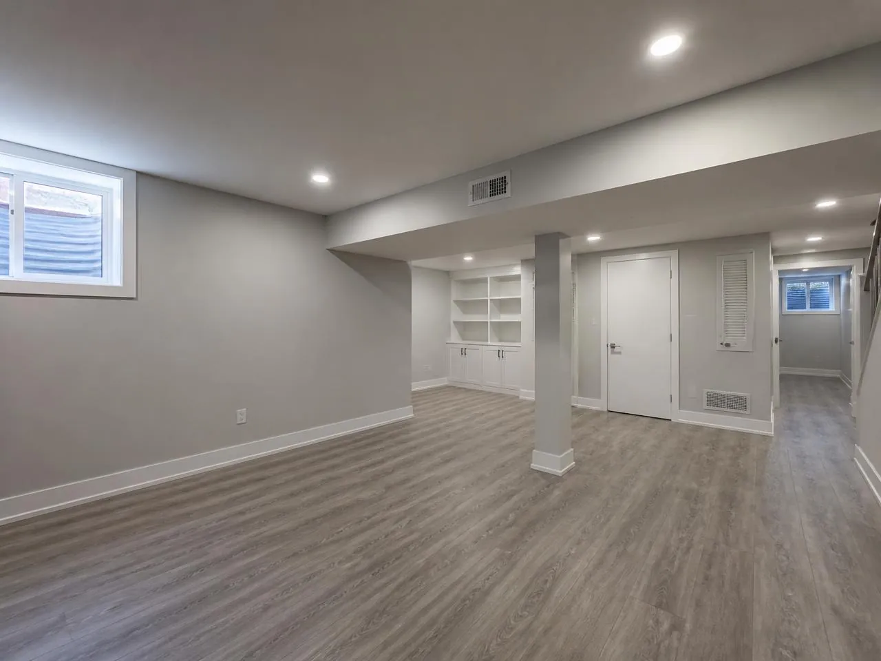 Finished basement by a general contractor in Staten Island with vinyl plank flooring and egress window