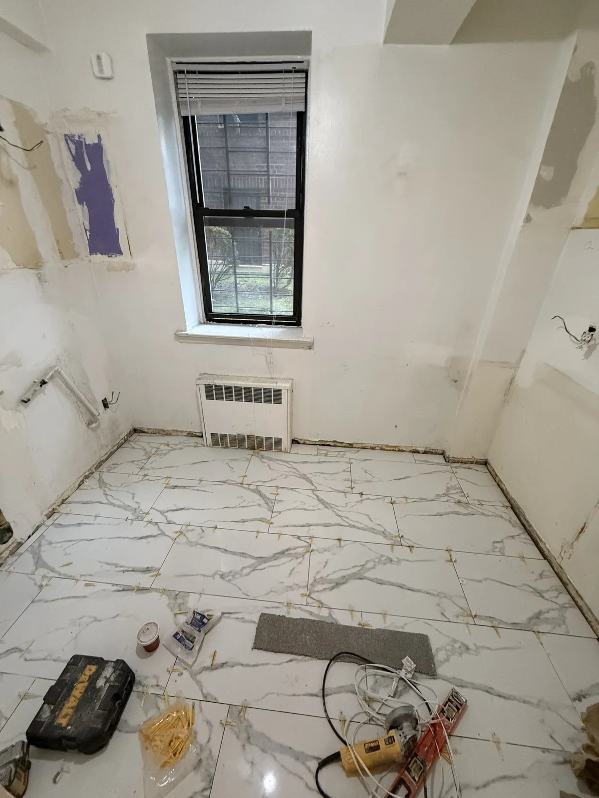 Marble-look porcelain floor tile installation during an apartment renovation in New York City
