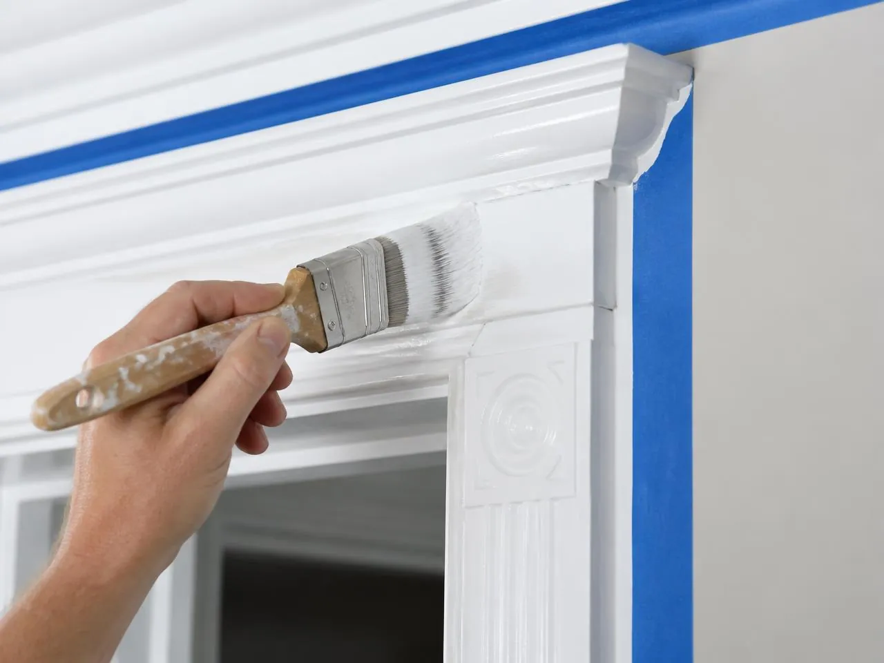 Brushing semi-gloss paint on crown molding during interior painting NYC
