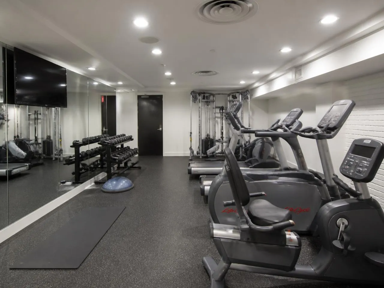 Basement fitness room conversion in a New York City residential building with rubber flooring and wall mirrors