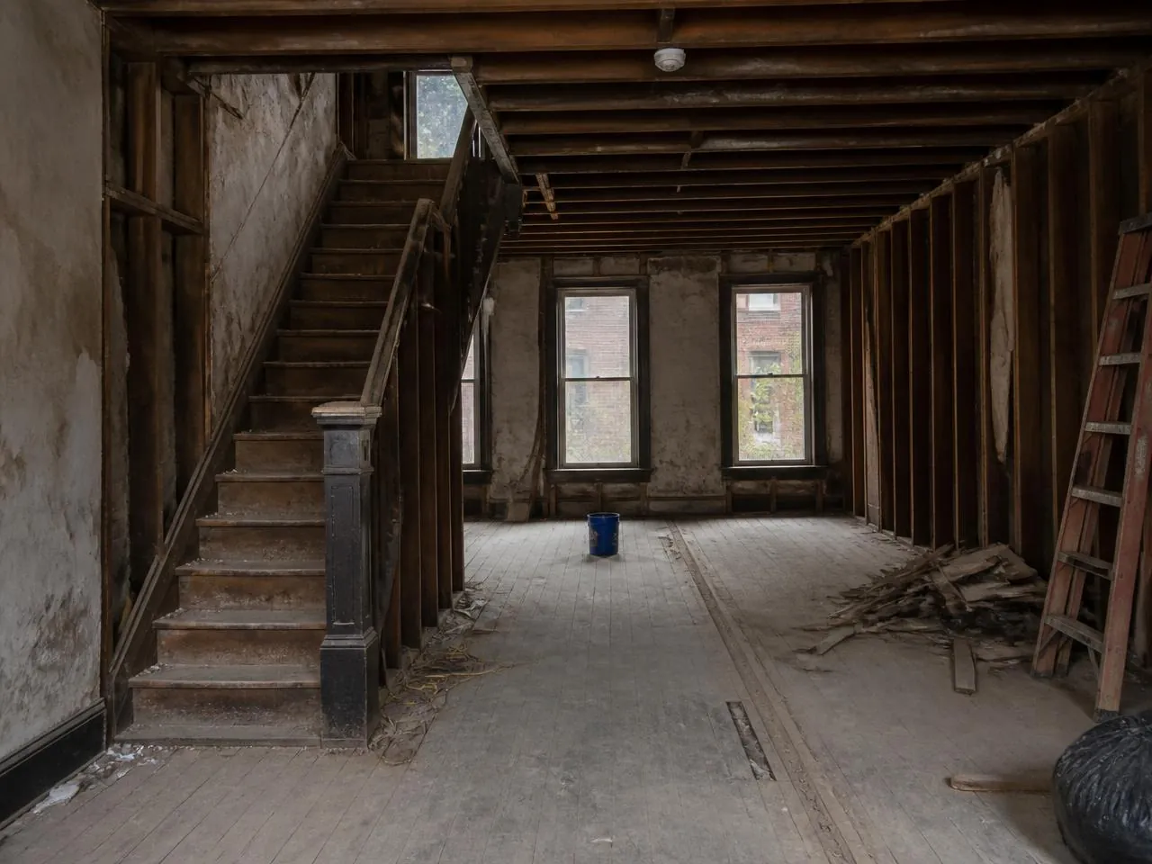 Before a townhouse renovation NYC with stripped plaster, exposed joists and a damaged original staircase
