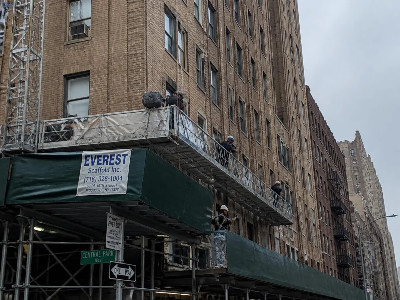 Sidewalk scaffolding and suspended scaffold on a Manhattan apartment facade during Local Law 11 compliance repairs