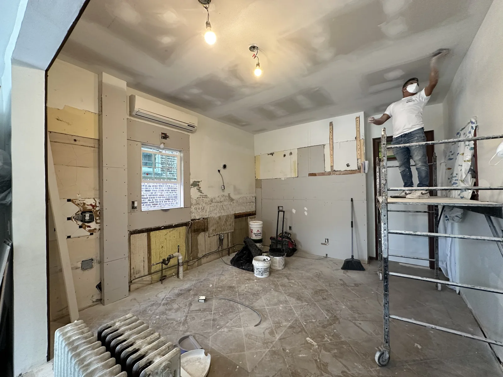 Kitchen renovation in progress with cabinets removed and ceiling skim coating in New York City