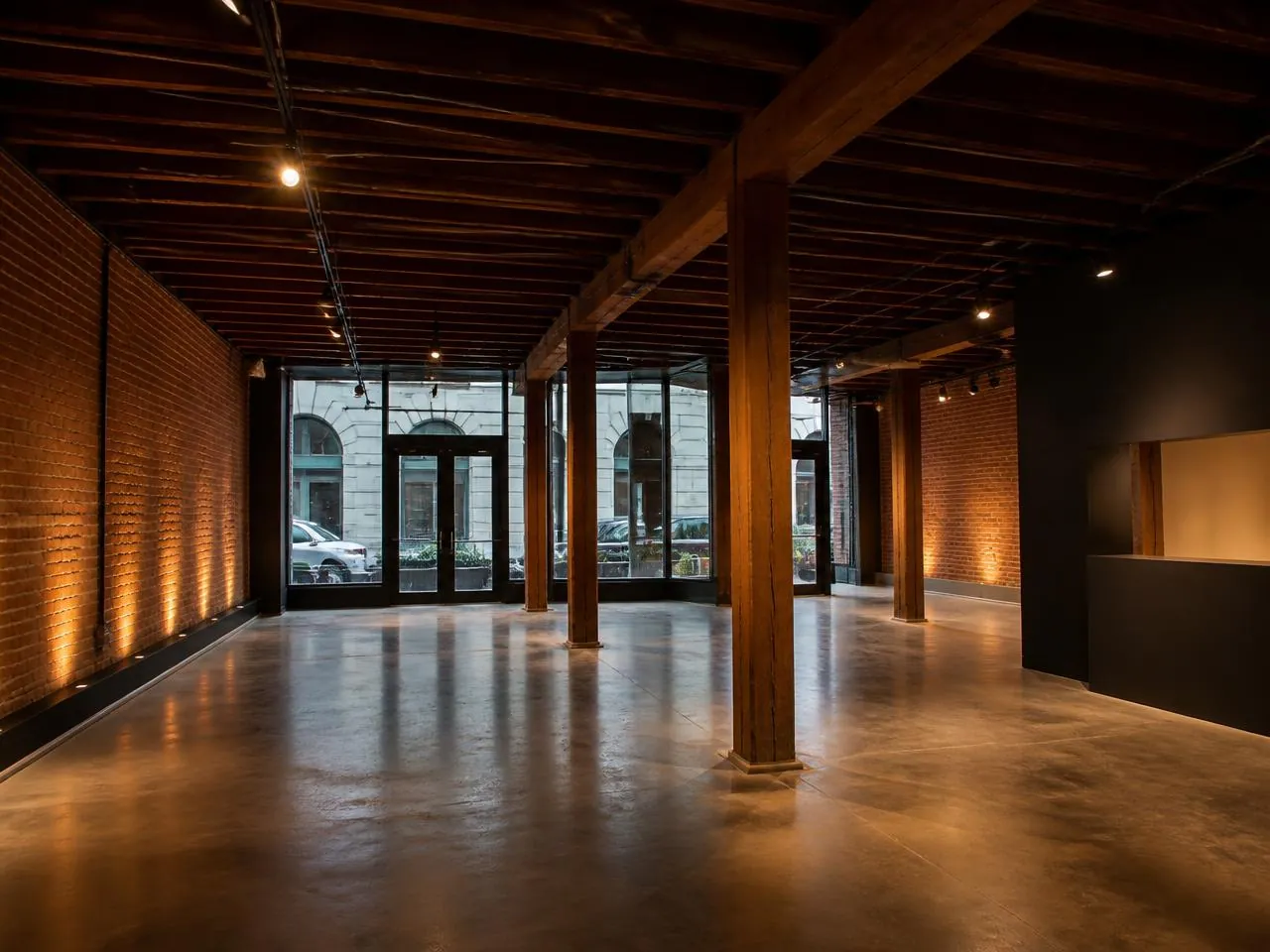 Completed ground-floor commercial buildout inside a historic Tribeca warehouse with exposed brick and timber ceiling