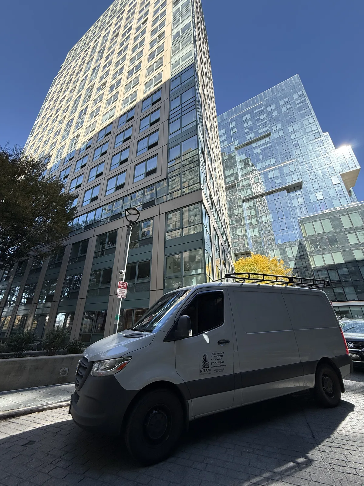 Melani Contracting branded van in front of glass residential towers in Manhattan