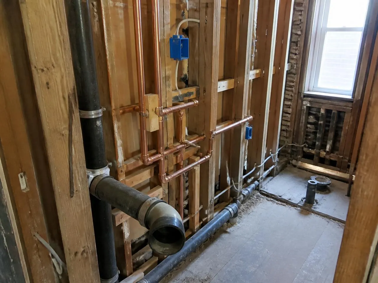 Demolition and plumbing rough-in with copper supply lines and cast iron waste piping during a bathroom renovation NYC project