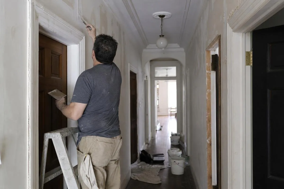 Worker repairing plaster near the ceiling in a hallway